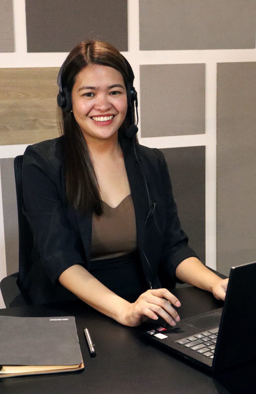 Mustard Seed support specialist with a headset at a laptop.